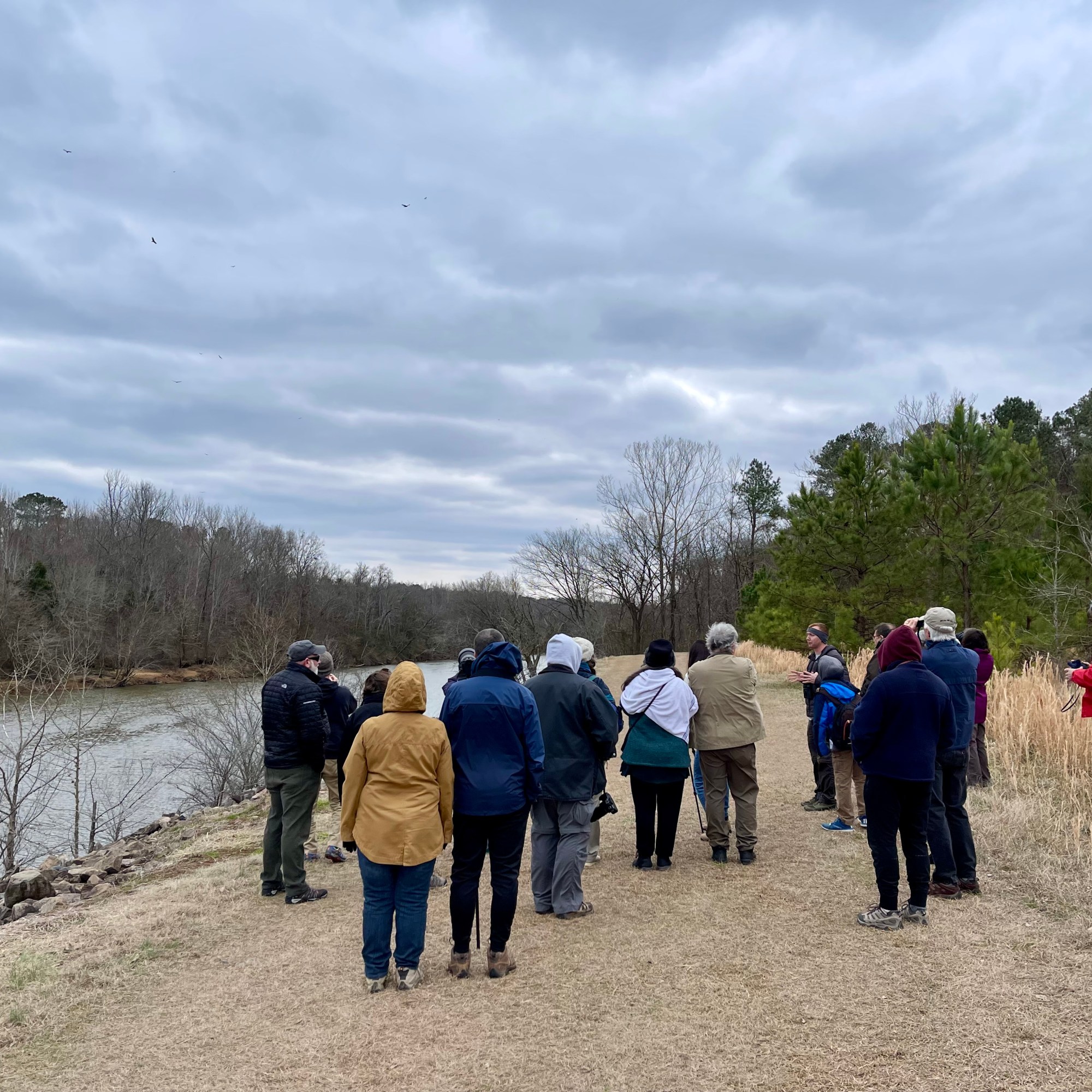 Group standing along the Haw River listening to eagle facts